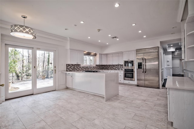 kitchen featuring tasteful backsplash, crown molding, hanging light fixtures, stainless steel appliances, and white cabinets