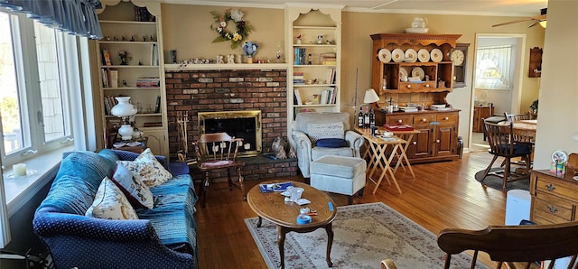 living room featuring hardwood / wood-style flooring, crown molding, ceiling fan, and a fireplace