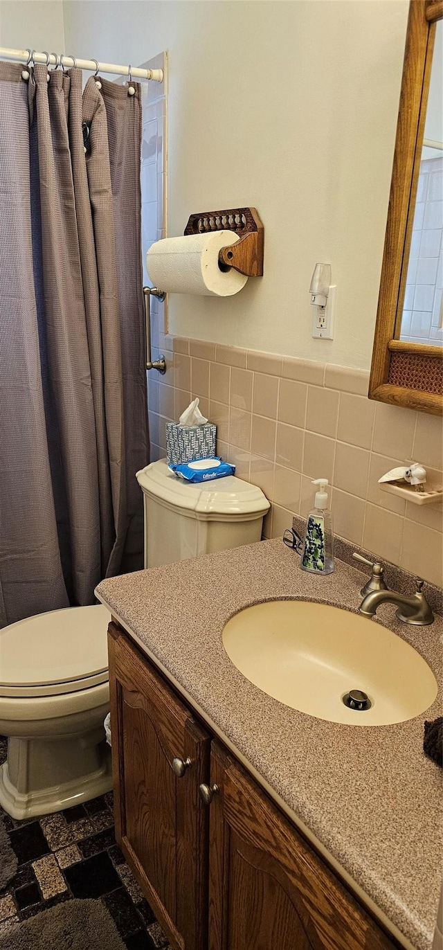 bathroom with vanity, toilet, curtained shower, and tile walls