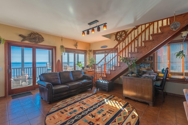 living room with a water view, track lighting, and dark tile patterned flooring