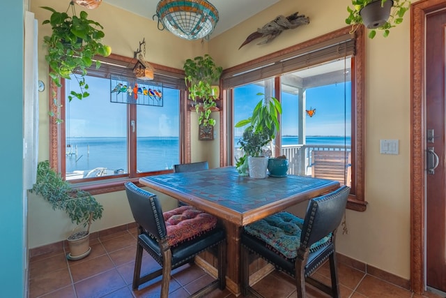 dining space featuring tile patterned floors, a healthy amount of sunlight, and a water view