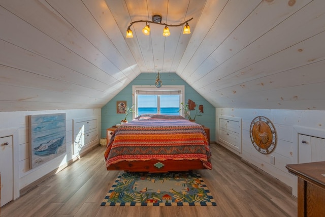 bedroom featuring vaulted ceiling, wooden walls, wood ceiling, and light hardwood / wood-style floors