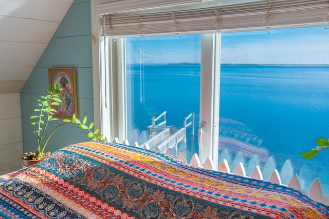 bedroom with lofted ceiling, multiple windows, and a water view