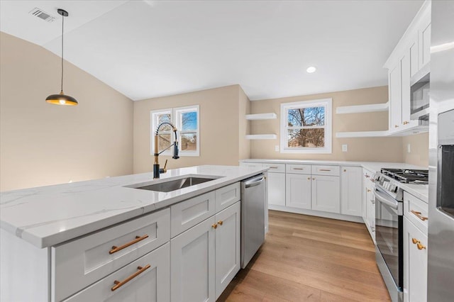 kitchen with light wood-style flooring, hanging light fixtures, stainless steel appliances, open shelves, and a sink