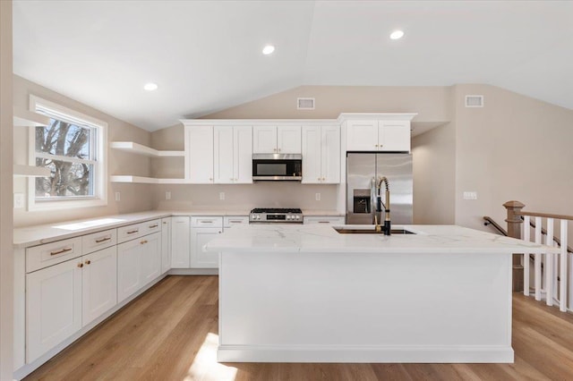 kitchen featuring a kitchen island with sink, a sink, visible vents, vaulted ceiling, and appliances with stainless steel finishes