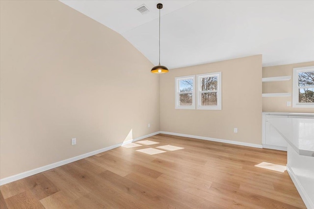 unfurnished dining area featuring light wood-type flooring, baseboards, visible vents, and lofted ceiling