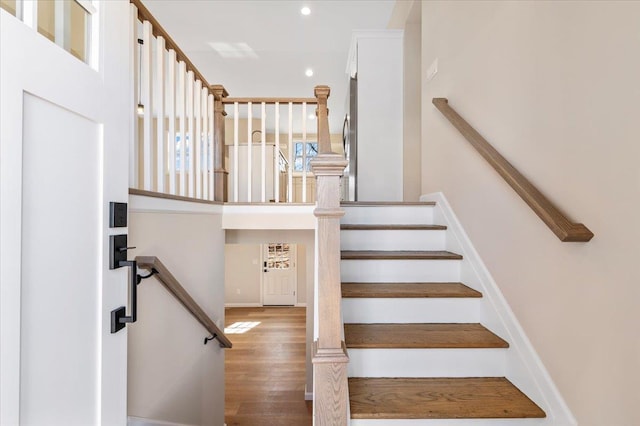 staircase with baseboards, wood finished floors, and recessed lighting