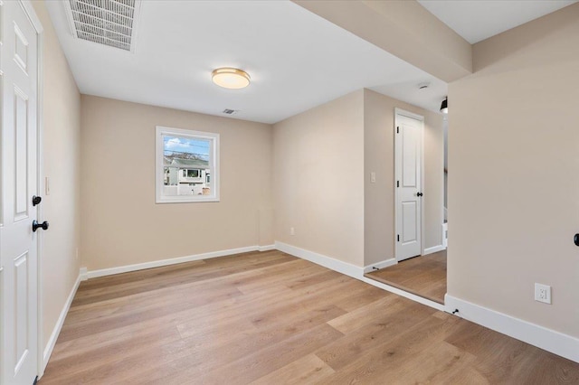 empty room with light wood-style floors, visible vents, and baseboards