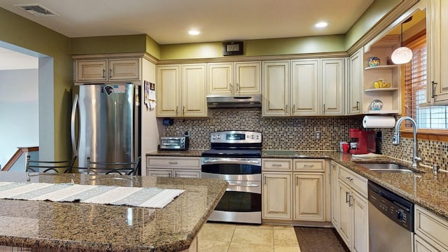 kitchen featuring sink, stainless steel appliances, tasteful backsplash, decorative light fixtures, and dark stone counters