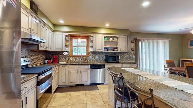 kitchen featuring sink, appliances with stainless steel finishes, dark stone countertops, backsplash, and cream cabinetry