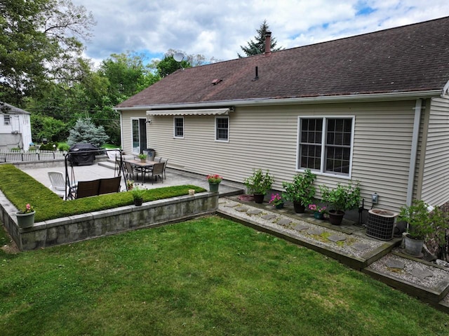 rear view of property featuring a lawn, cooling unit, and a patio area