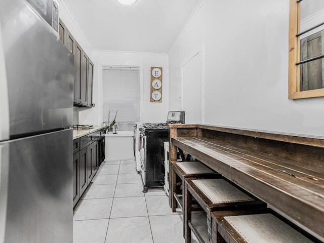 kitchen with light stone countertops, crown molding, light tile patterned flooring, and appliances with stainless steel finishes