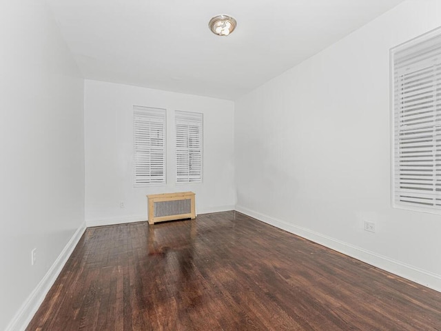 unfurnished room featuring radiator and dark wood-type flooring