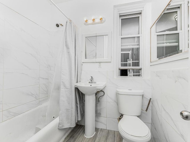 bathroom with shower / tub combo with curtain, tile walls, and toilet