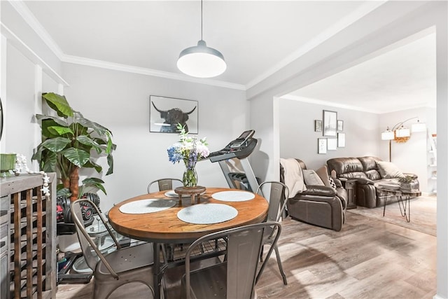 dining space with ornamental molding and light wood-type flooring