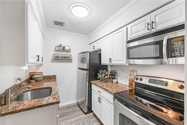 kitchen featuring stainless steel appliances, white cabinetry, and dark stone counters