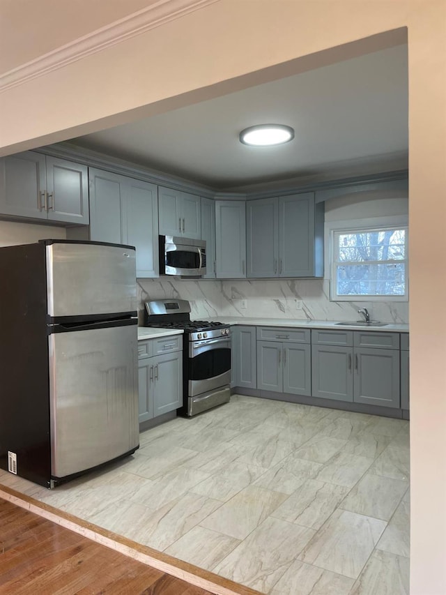 kitchen with crown molding, appliances with stainless steel finishes, gray cabinets, and sink