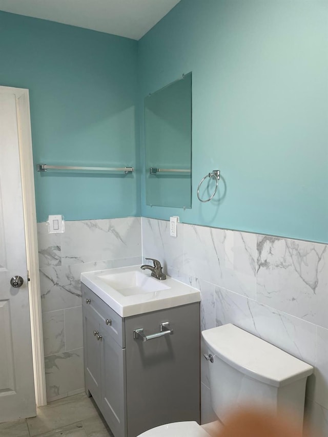 bathroom with vanity, tile walls, and toilet