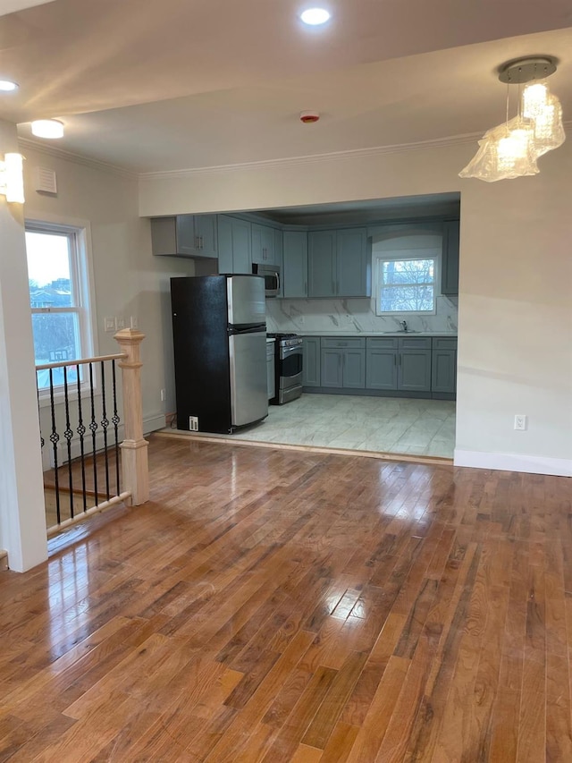 kitchen featuring stainless steel appliances, hanging light fixtures, gray cabinetry, and light wood-type flooring