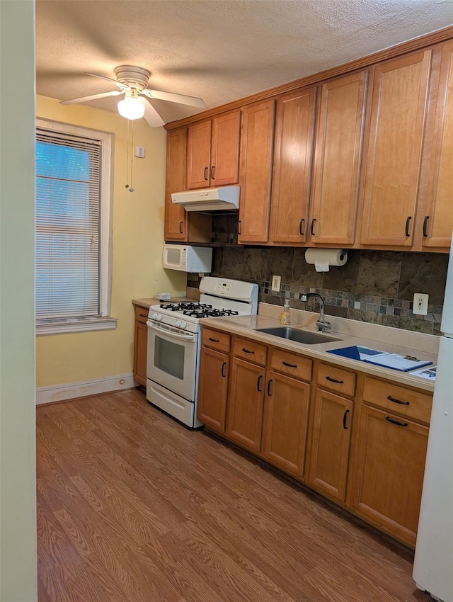 72-34 Austin St Unit D4, Forest Hills, NY 11375 - kitchen with white appliances, under cabinet range hood, decorative backsplash, wood finished floors, and light countertops