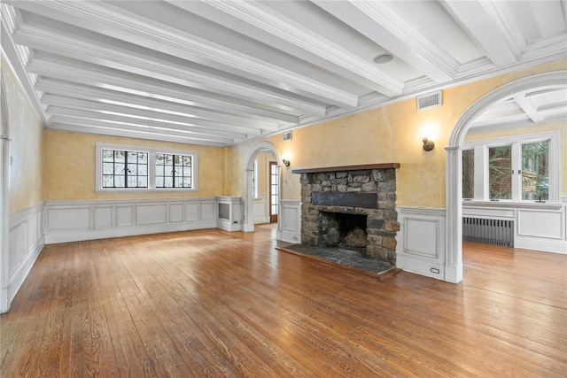 unfurnished living room featuring radiator, a fireplace, beamed ceiling, hardwood / wood-style flooring, and crown molding