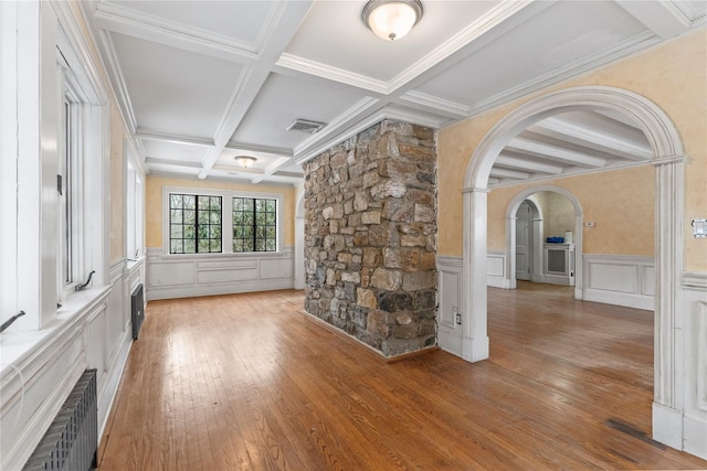 unfurnished living room with coffered ceiling, radiator, wood-type flooring, and beamed ceiling