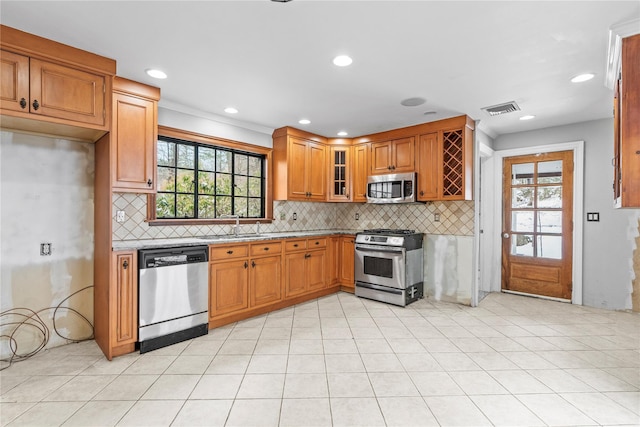 kitchen featuring appliances with stainless steel finishes, light stone countertops, decorative backsplash, and a wealth of natural light