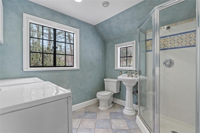 bathroom with washer and clothes dryer, vaulted ceiling, tile patterned floors, toilet, and walk in shower