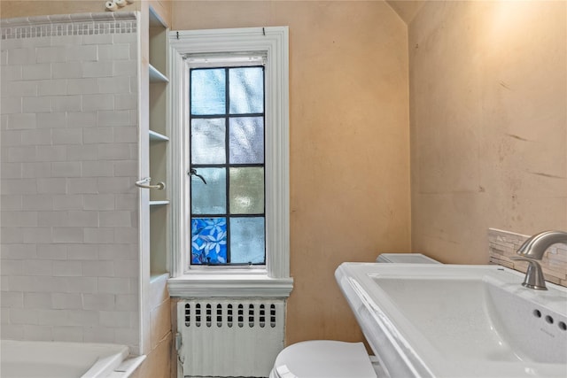 bathroom with sink, radiator heating unit, toilet, and a tub to relax in