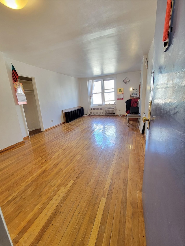 unfurnished living room with light wood-style floors, radiator heating unit, and baseboards