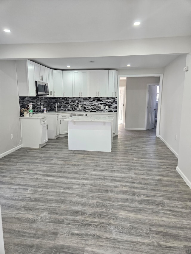 kitchen with white cabinetry, tasteful backsplash, a center island, and light hardwood / wood-style flooring