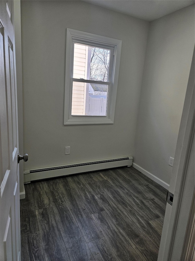 spare room featuring dark hardwood / wood-style flooring and a baseboard heating unit