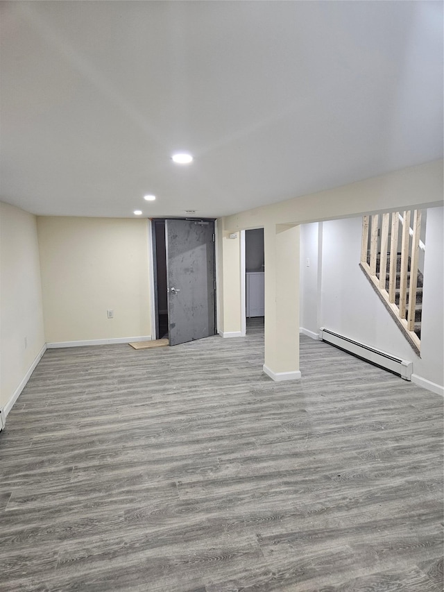 basement with a baseboard heating unit and light hardwood / wood-style flooring