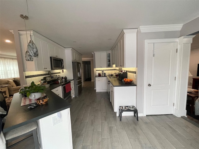 kitchen featuring white cabinets, backsplash, stainless steel appliances, crown molding, and light hardwood / wood-style flooring