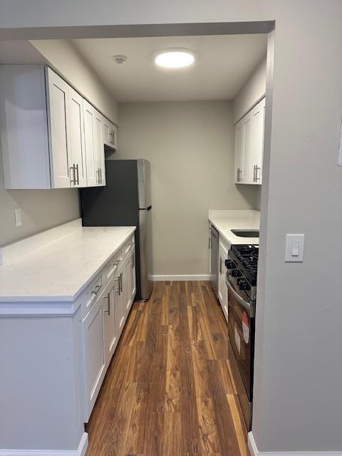 kitchen with white cabinetry, appliances with stainless steel finishes, and dark wood-type flooring