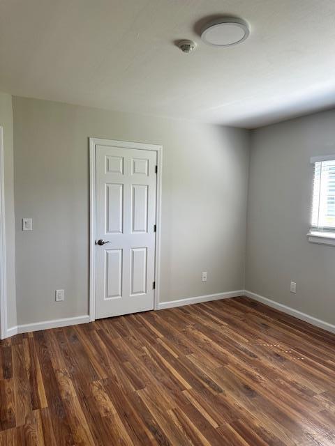 unfurnished room with dark hardwood / wood-style flooring