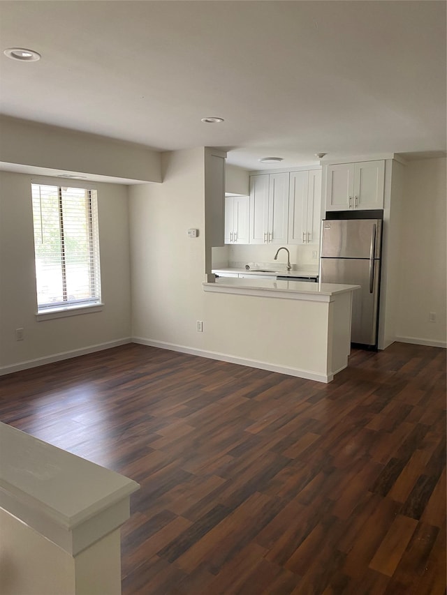 kitchen featuring stainless steel refrigerator, dark hardwood / wood-style floors, kitchen peninsula, and white cabinets