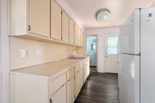 kitchen with dark hardwood / wood-style flooring, sink, white fridge, and cream cabinetry