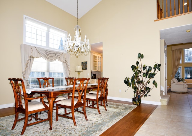 tiled dining room featuring a towering ceiling and a chandelier