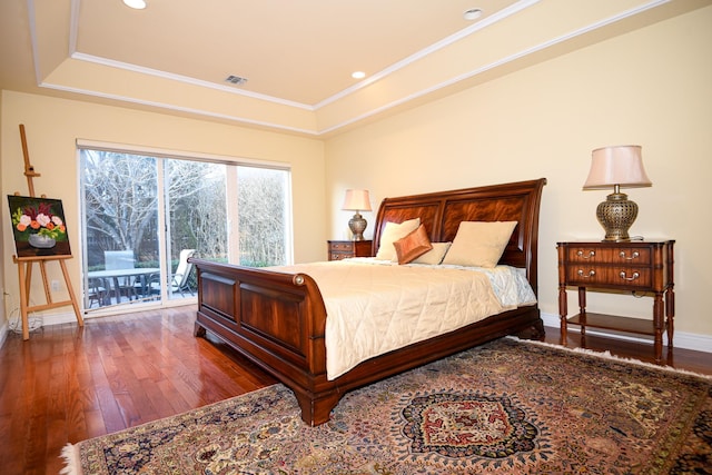 bedroom featuring crown molding, hardwood / wood-style floors, access to exterior, and a tray ceiling