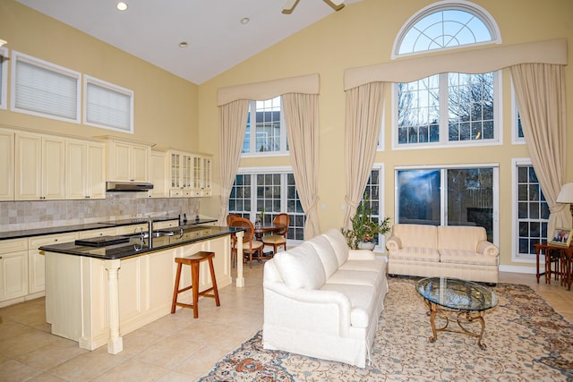 living room featuring sink, a towering ceiling, a wealth of natural light, and light tile patterned floors