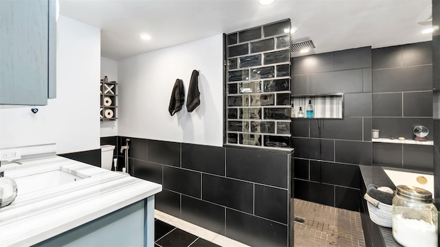 bathroom with vanity, tiled shower, tile walls, and tile patterned floors