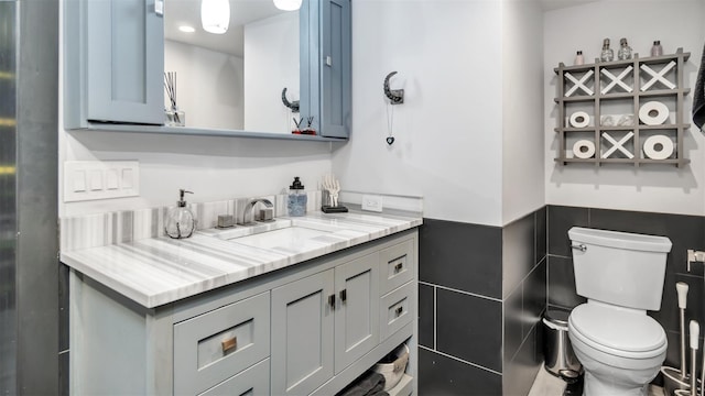 bathroom featuring vanity, tile walls, and toilet