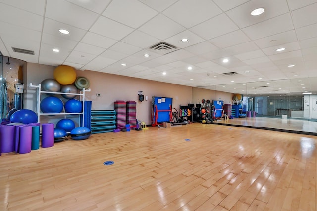 exercise room with a drop ceiling and light hardwood / wood-style floors