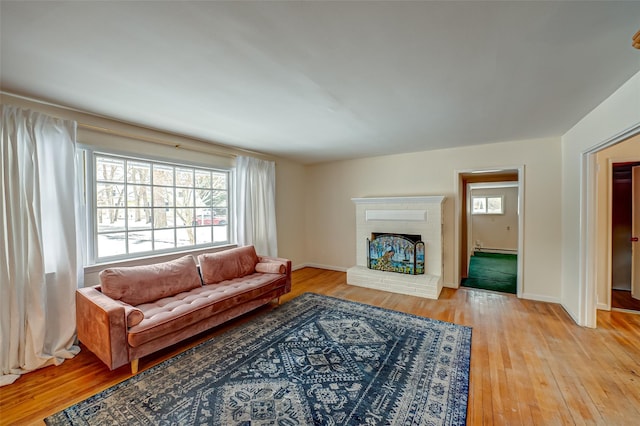 living room featuring a baseboard radiator, a brick fireplace, and light hardwood / wood-style flooring