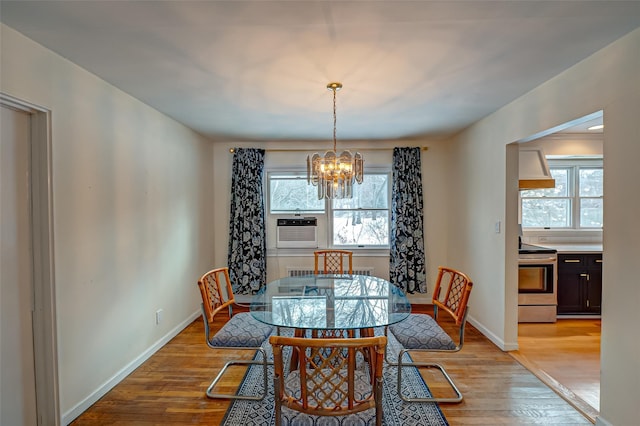 dining area featuring cooling unit, a notable chandelier, a wealth of natural light, and light wood-type flooring