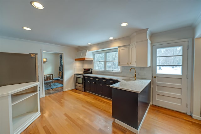 kitchen featuring sink, white cabinets, stainless steel range with electric cooktop, custom exhaust hood, and light hardwood / wood-style floors