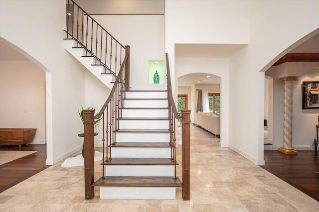 stairway with hardwood / wood-style floors and a towering ceiling