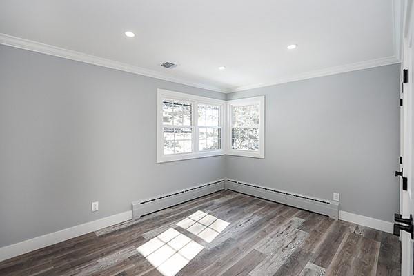 unfurnished room featuring ornamental molding, wood finished floors, and baseboards