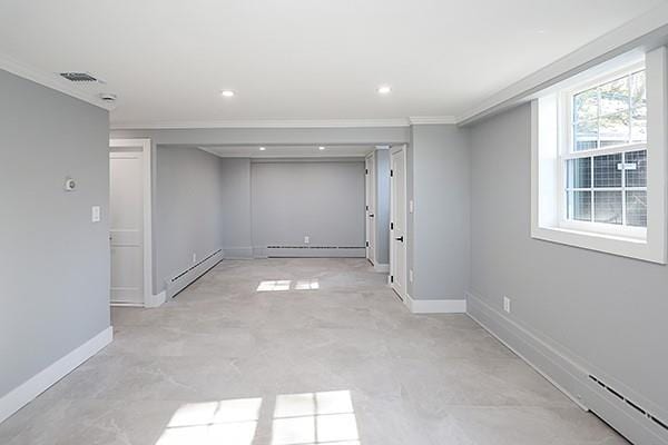 basement with ornamental molding, a baseboard radiator, visible vents, and baseboards